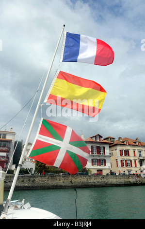 Trois drapeaux flottants à partir d'un mât du bateau, de bas en haut : drapeau Basque, drapeau espagnol, pavillon français, à St Jean de Luz, France Banque D'Images