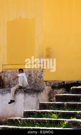 Un homme est assis à l'extérieur d'un mur peint de couleurs vives à Granada Nicaragua Banque D'Images