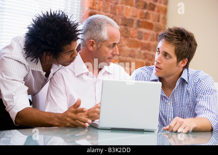 Trois hommes d'en parler avec un ordinateur portable de bureau Banque D'Images