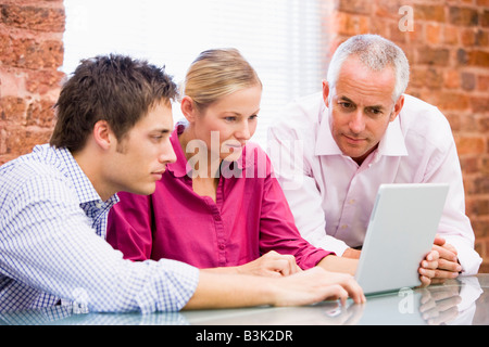 Trois businesspeople in office looking at laptop Banque D'Images