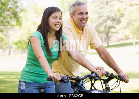 Man and girl on bikes outdoors smiling Banque D'Images