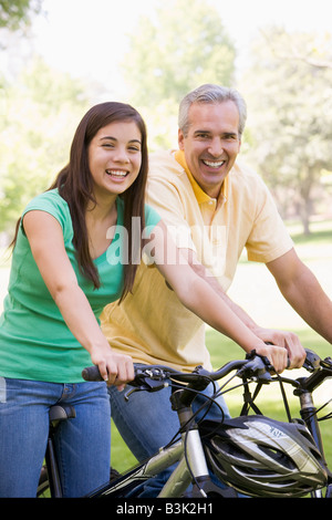 Man and girl on bikes outdoors smiling Banque D'Images