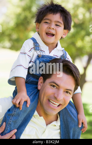 Man giving Young boy épaule ride outdoors smiling Banque D'Images