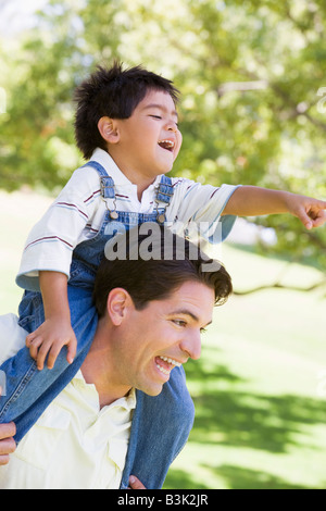 Man giving Young boy épaule ride outdoors smiling Banque D'Images