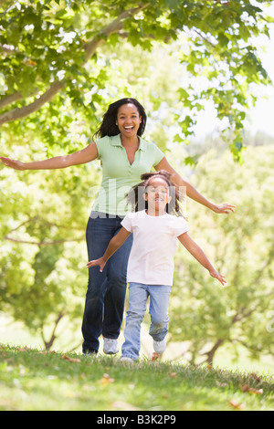 Femme et jeune fille courir outdoors smiling Banque D'Images