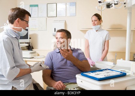 Dentiste et assistant en salle d'examen avec l'homme en souriant président Banque D'Images