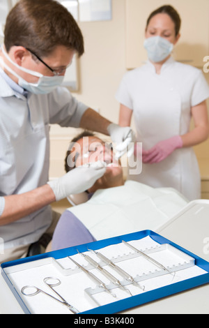 Dentiste et assistant en salle d'examen avec l'homme en fauteuil Banque D'Images