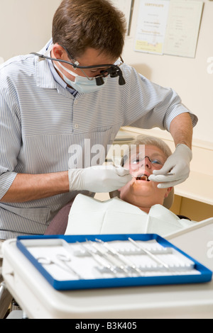 Dentiste dans la salle d'examen avec femme en fauteuil Banque D'Images