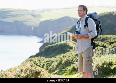 Homme debout sur le chemin perché holding map Banque D'Images