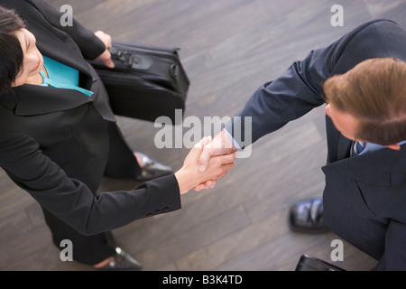 Deux businesspeople standing indoors shaking hands Banque D'Images