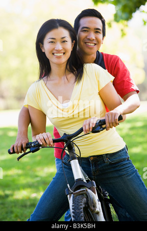 Couple on a bike outdoors smiling Banque D'Images