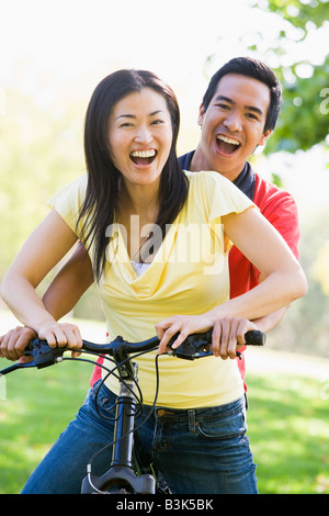 Couple on a bike outdoors smiling Banque D'Images