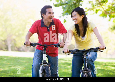 Couple on bikes outdoors smiling Banque D'Images