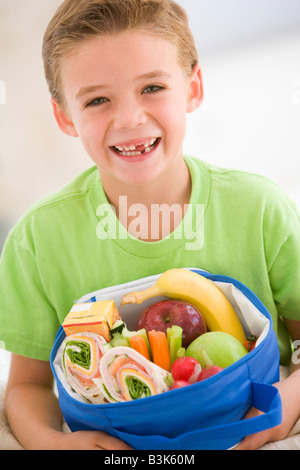 Young boy holding panier-repas dans la salle de séjour smiling Banque D'Images