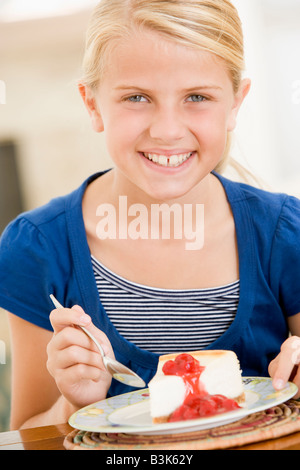 Jeune fille à l'intérieur manger cheesecake smiling Banque D'Images