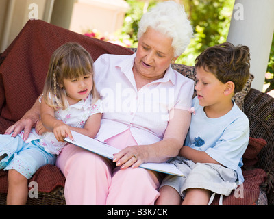 Grand-mère à la lecture des petits-enfants. Banque D'Images