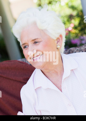 Senior woman sitting en plein air sur une chaise Banque D'Images
