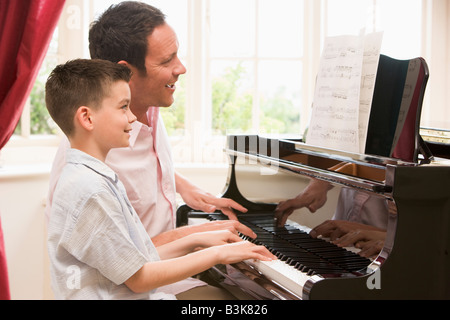 L'homme et jeune garçon jouant du piano et souriant Banque D'Images