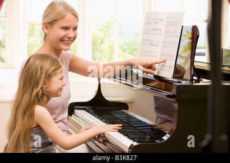 Woman and young girl playing piano and smiling Banque D'Images