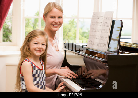 Woman and young girl playing piano and smiling Banque D'Images