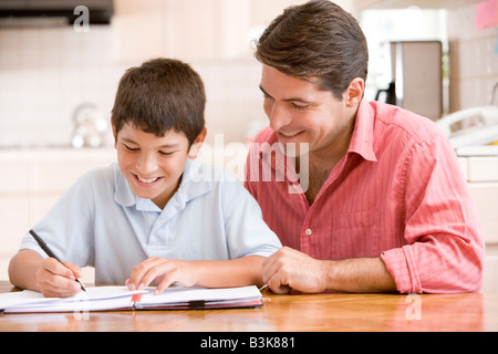 Aider l'homme jeune garçon dans la cuisine à faire des devoirs et smiling Banque D'Images