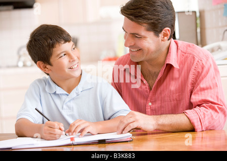 Aider l'homme jeune garçon dans la cuisine à faire des devoirs et smiling Banque D'Images