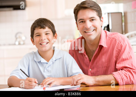 Aider l'homme jeune garçon dans la cuisine à faire des devoirs et smiling Banque D'Images