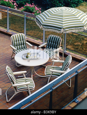 Mobilier de jardin SUR UNE TERRASSE FAUTEUILS ET PARASOL DÉCORÉ DE TISSU rayé vert Banque D'Images