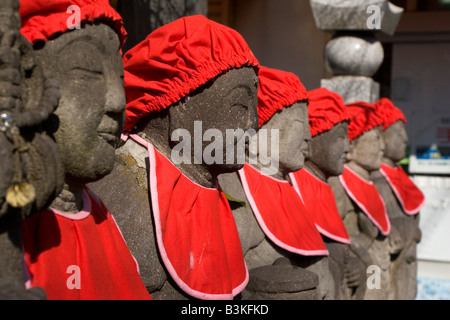 Statues Jizo de pierre sont décorées avec red bavoirs et chapeaux. Banque D'Images