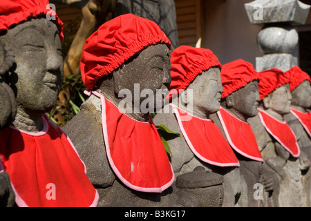 Statues Jizo de pierre sont décorées avec red bavoirs et chapeaux. Banque D'Images