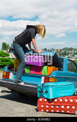 Femme loading coffre de voiture avec des valises Banque D'Images