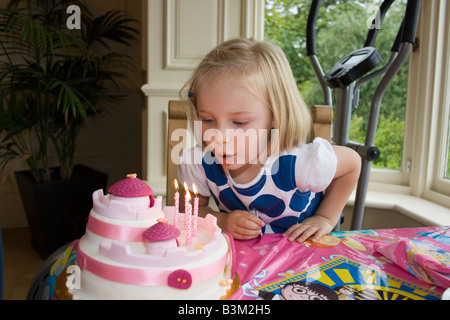 UK 4 year old girl blowing out candles on cake Banque D'Images