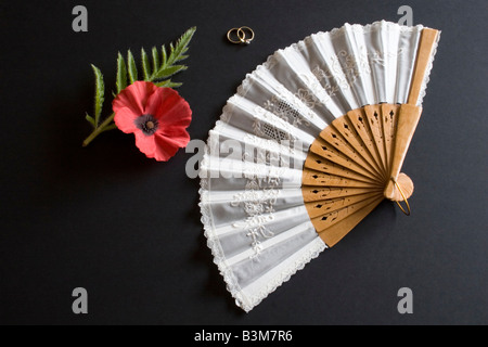 Ventilateur pliant blanc Oriental sur fond noir avec des anneaux et pavot rouge Banque D'Images