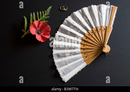 Ventilateur pliant blanc Oriental sur fond noir avec des anneaux et pavot rouge Banque D'Images