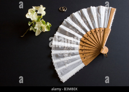 Ventilateur pliant blanc Oriental sur fond noir avec des fleurs et des anneaux Banque D'Images