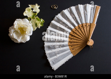 Ventilateur pliant blanc Oriental sur fond noir avec des fleurs et des anneaux Banque D'Images