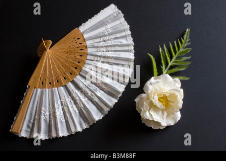 Pliage blanc oriental fan sur un fond noir avec fleur Banque D'Images