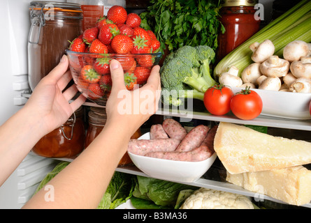 WOMAN TAKING BOL DE FRAISES FRAÎCHES DE RÉFRIGÉRATEUR Banque D'Images