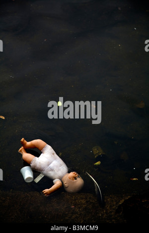 Poupée pour enfants jetés dans l'eau d'ordures Banque D'Images