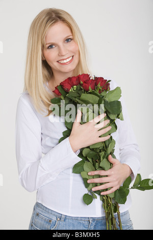 Jeune femme tenant un bouquet de roses, smiling, portrait Banque D'Images