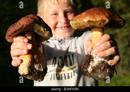 Jeune garçon montrant deux énormes cèpes (Boletus edulis) sur le lac Onega, en Carélie, Russie Banque D'Images