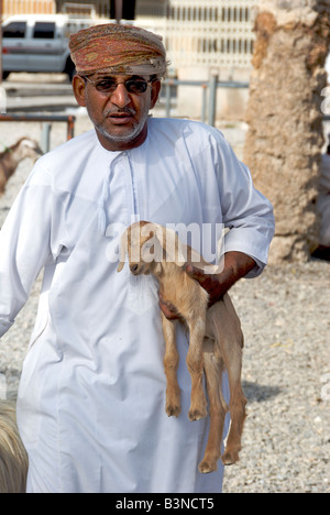 Homme portant l'élevage de chèvres de bébé ou Souq Al Dakhiliyah Nizwa marché Région Sultanat d'Oman Banque D'Images