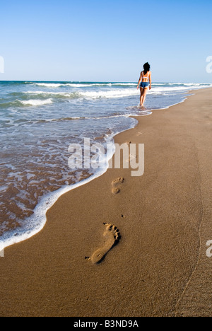 Parution modèle femme marche dans la distance en laissant des traces de pas dans le sable humide. El Saler. Valence. Espagne Banque D'Images