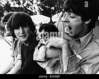 Le Beatles John Lennon et Paul McCartney se détendre avec un chiot aux Bahamas vers 1965 Banque D'Images