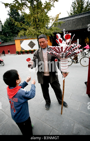 Garçon chinois l'achat des bonbons de l'homme au monastère de Shu Wen Banque D'Images