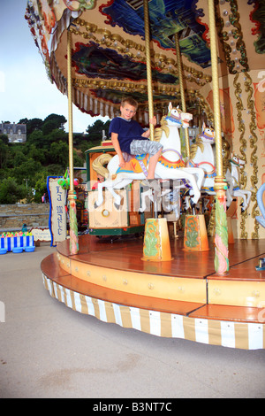 Garçon de 9 ans sur carrousel (rond-point) à St Cast le Guildo, Côtes d'Armor, Bretagne, France, Europe Banque D'Images