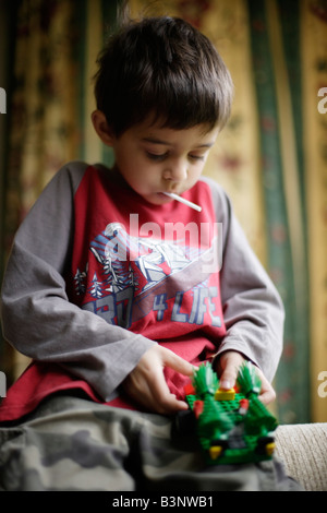 Garçon de 6 ans suce une sucette tout en construisant avec des briques en plastique jouet Banque D'Images