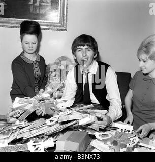 Février 1964 Les Beatles George Harrison des Beatles avec ventilateur secrétaire du club Anne Collingham aidant à trier les 52 sacs pleins de cartes de vœux et des colis qu'il a reçue de fans pour son 21e anniversaire Banque D'Images