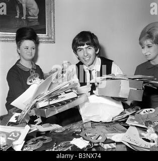 Février 1964 Les Beatles George Harrison des Beatles avec ventilateur secrétaire du club Anne Collingham aidant à trier les 52 sacs pleins de cartes de vœux et des colis qu'il a reçue de fans pour son 21e anniversaire Banque D'Images