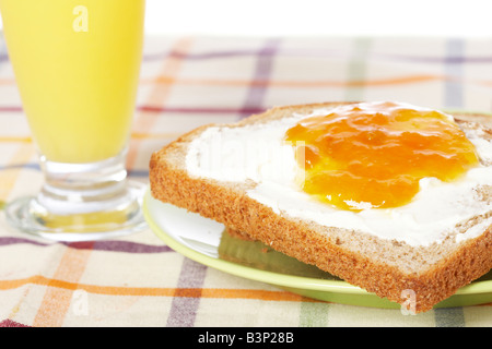 Pain grillé avec du beurre et de la confiture de pêches dans la plaque verte avec soft shadow sur tapis carrés profondeur de champ à l'arrière-plan Banque D'Images